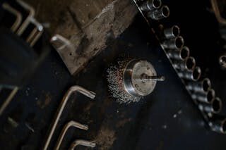 Close-up of wire brush and assorted tools on a workshop table, ideal for industrial and mechanical themes.