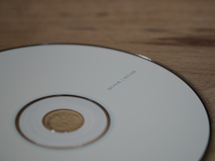 white compact disc on brown wooden table